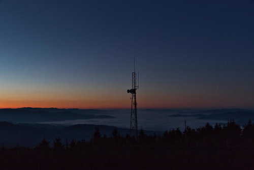 山並みを望む鉄塔と雲海に映える朝焼けの日の出風景
