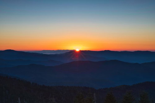 山並みの稜線から昇る眩しすぎる朝日と放射状の光線
