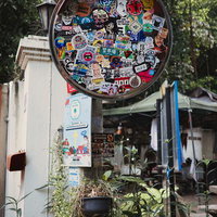 路地裏のカーブミラーを彩る多数のステッカーの写真
