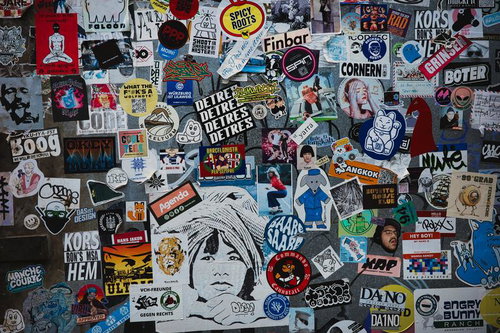 カラフルで隙間なく重なった数百枚のステッカーとシールの密集コラージュ壁面