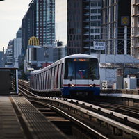 バンコクの高層ビル群を背景に走行するBTSスカイトレイン車両の写真