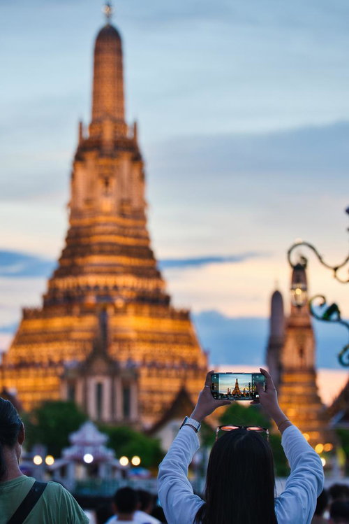 スマートフォンでワット・アルンを撮影する観光客の夕暮れ時