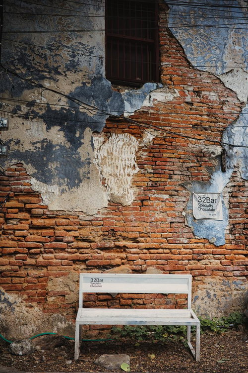 剥がれた塗装の壁面と白いベンチ