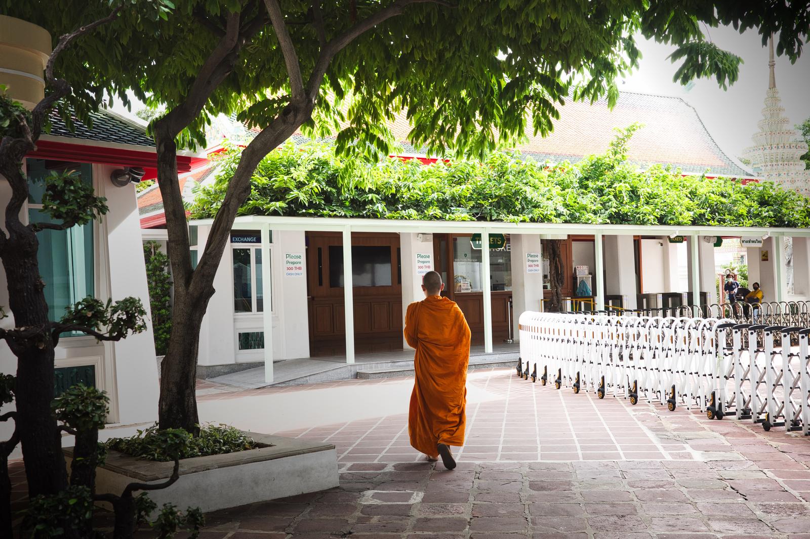 オレンジ色の袈裟を着た僧侶が寺院の中庭を歩いている