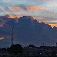 夕焼け空に立ち上がる巨大な積乱雲と都市の通信アンテナの写真