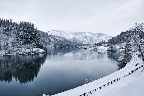只見線沿線の雪山と川が映る冬景色