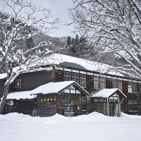 雪積もる樹木に囲まれた喰丸小学校の木造校舎の写真