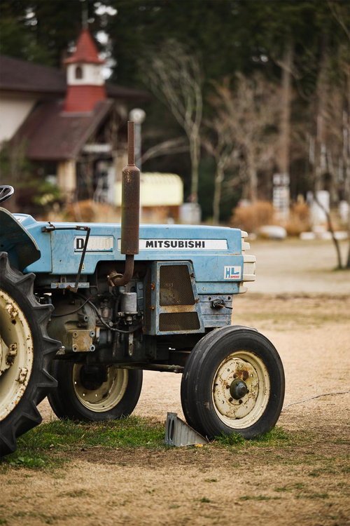 空色のボディに錆びた部品が付いた古いミツビシトラクター