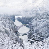 冬の第一只見川橋梁を渡る列車と雪景色の写真