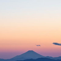 夕焼け空に浮かぶ富士山のシルエット、夜景の街明かりと共に映える情景の写真