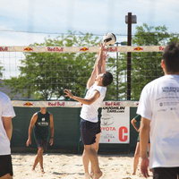 ビーチバレーの試合でボールをトスするプレイヤーの写真