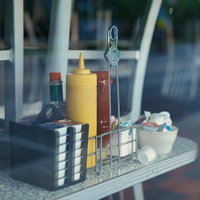 窓越しに並ぶケチャップとマスタードのボトルの写真
