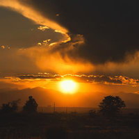 夕焼けにたなびく雲のシルエット、地平線の太陽が照らす風景の写真