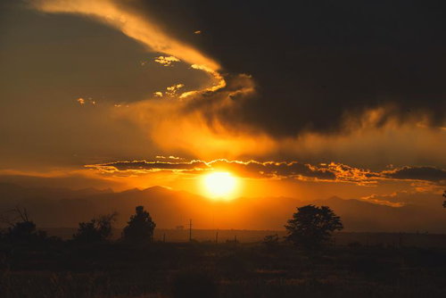 夕焼けにたなびく雲のシルエット、地平線の太陽が照らす風景