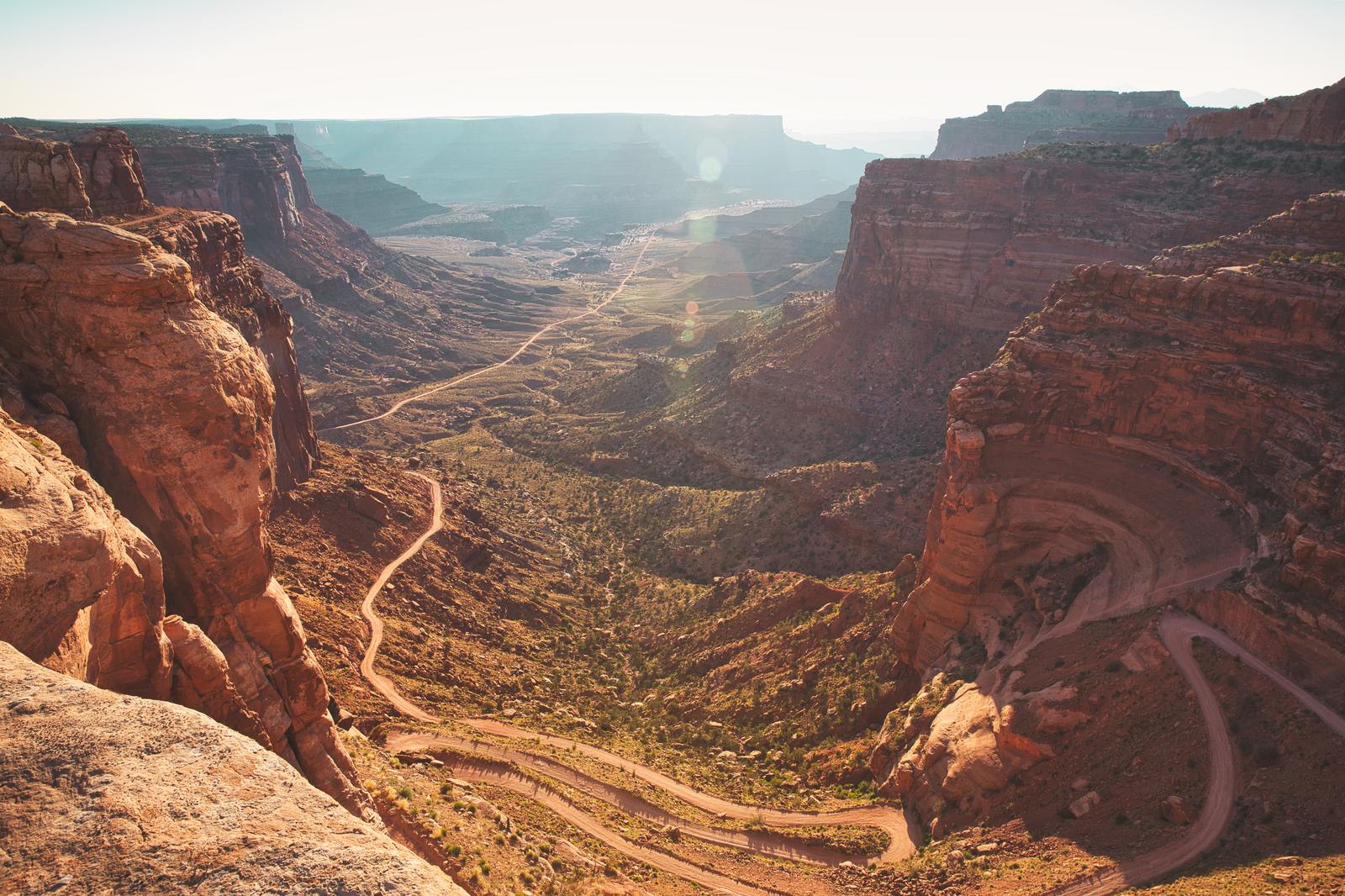 キャニオンランズ国立公園のシャファートレイルの展望。赤い砂岩の崖と蛇行する道路が見える渓谷風景