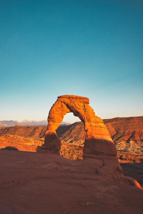 アーチズ国立公園のデリケートアーチ、夕焼けに染まる赤岩の天然石造アーチ