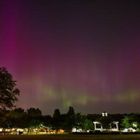 公園のガゼボを照らすピンク色のオーロラと星空の写真