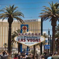 ウェルカム看板とマンダレイ・ベイ、ヤシの木が並ぶラスベガスの街並みの写真
