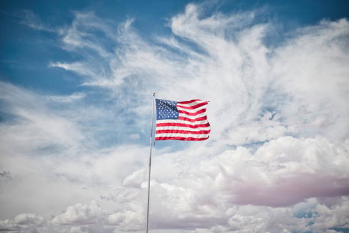 青空に翻るアメリカの星条旗が風になびく愛国心を表現する国旗
