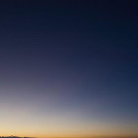 薄暗い空に浮かぶ三日月とグランドキャニオンの地平線の写真