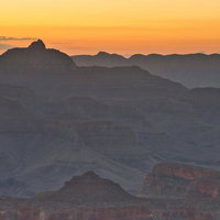 夕暮れのグランドキャニオンとシルエットの山々が連なる大峡谷の写真