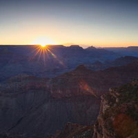 グランドキャニオンの渓谷を照らす朝日と光芒の写真