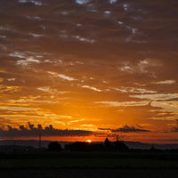 地平線から昇る朝日とオレンジ色に染まる雲海の夜明けの写真