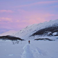 雪に覆われた山々と広大な雪原を歩く登山者の写真
