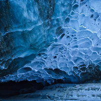 青い氷河の洞窟内に広がる氷壁の模様と結晶構造の写真