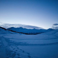 雪原の足跡と雪に覆われた山々が広がりの写真