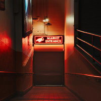 赤いネオン看板が光るマーケット入口の通路の写真