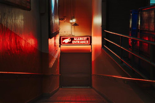 赤いネオン看板が光るマーケット入口の通路