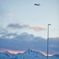冬の夕暮れに映える雪山と飛行機の離陸風景の写真