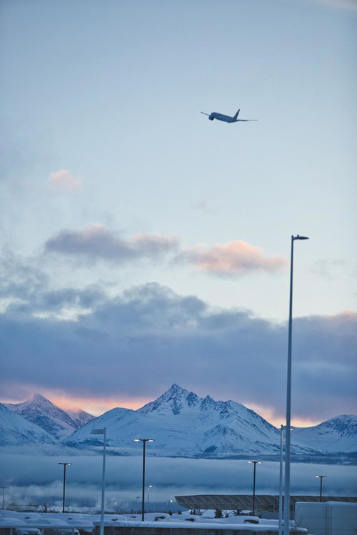 冬の夕暮れに映える雪山と飛行機の離陸風景
