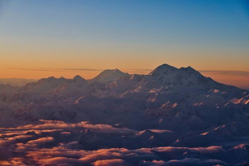 オレンジ色に染まる夕暮れのデナリの雪山と雲海