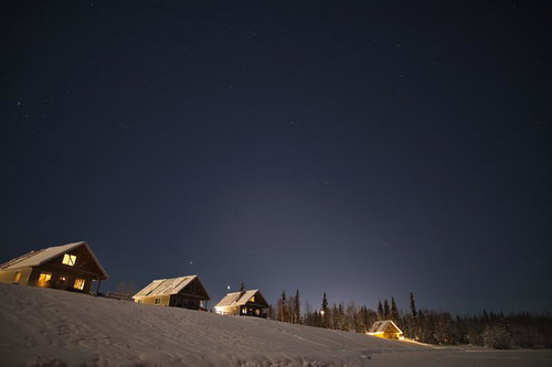 冬の星空の下で静かに佇む雪の丘の山小屋の夜景