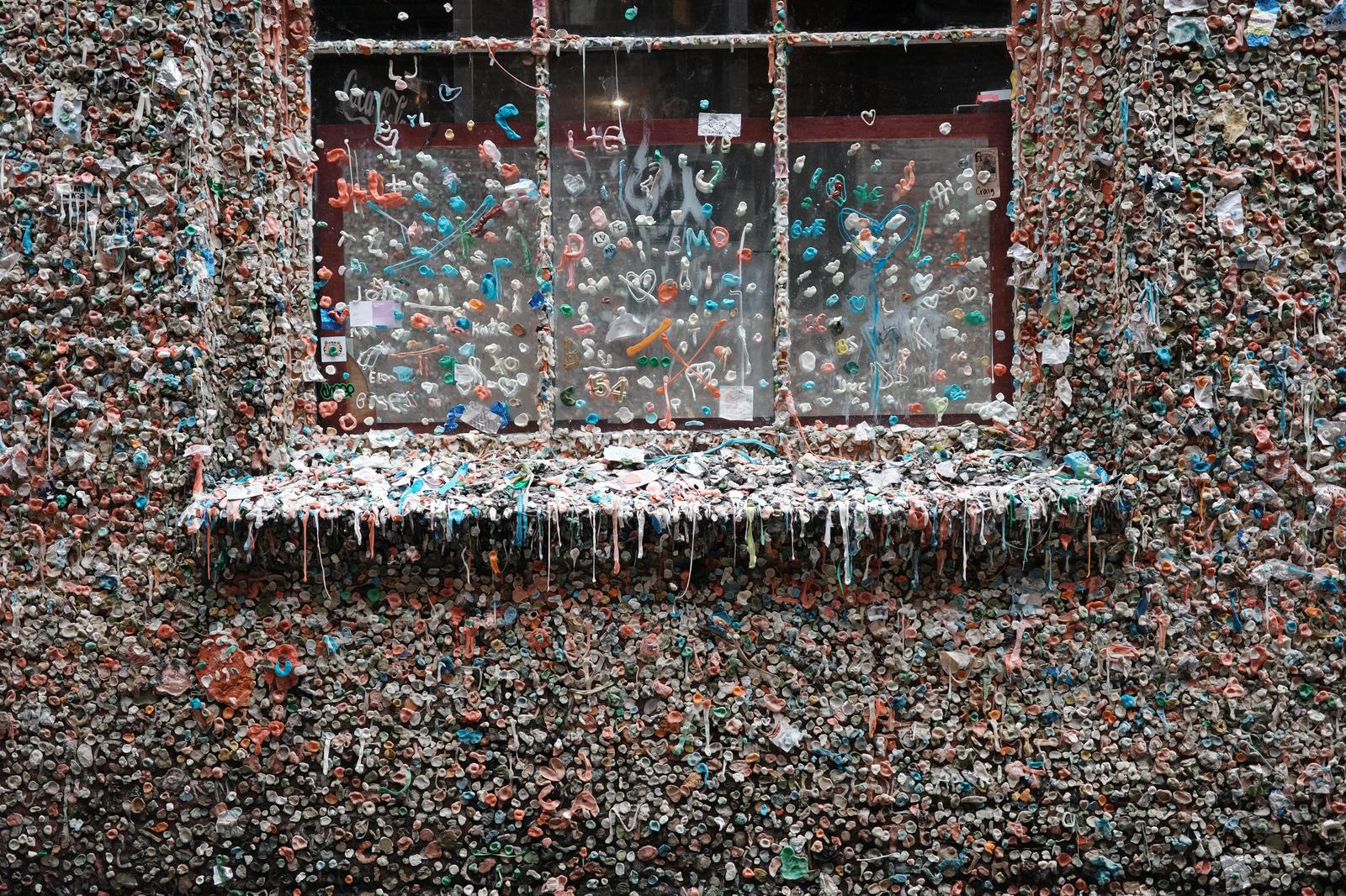 赤や緑、白のカラフルなガムで埋め尽くされた壁と窓のストリートアート作品
