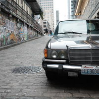 ウォールアートが映える石畳の坂道に停められたクラシックメルセデスベンツの写真
