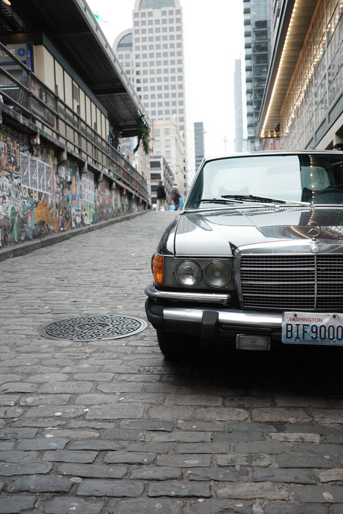 ウォールアートが映える石畳の坂道に停められたクラシックメルセデスベンツ
