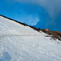 雪原に続く山道と山小屋の写真