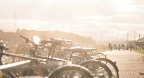 夕焼けに染まる河川敷に駐輪する自転車と夕景