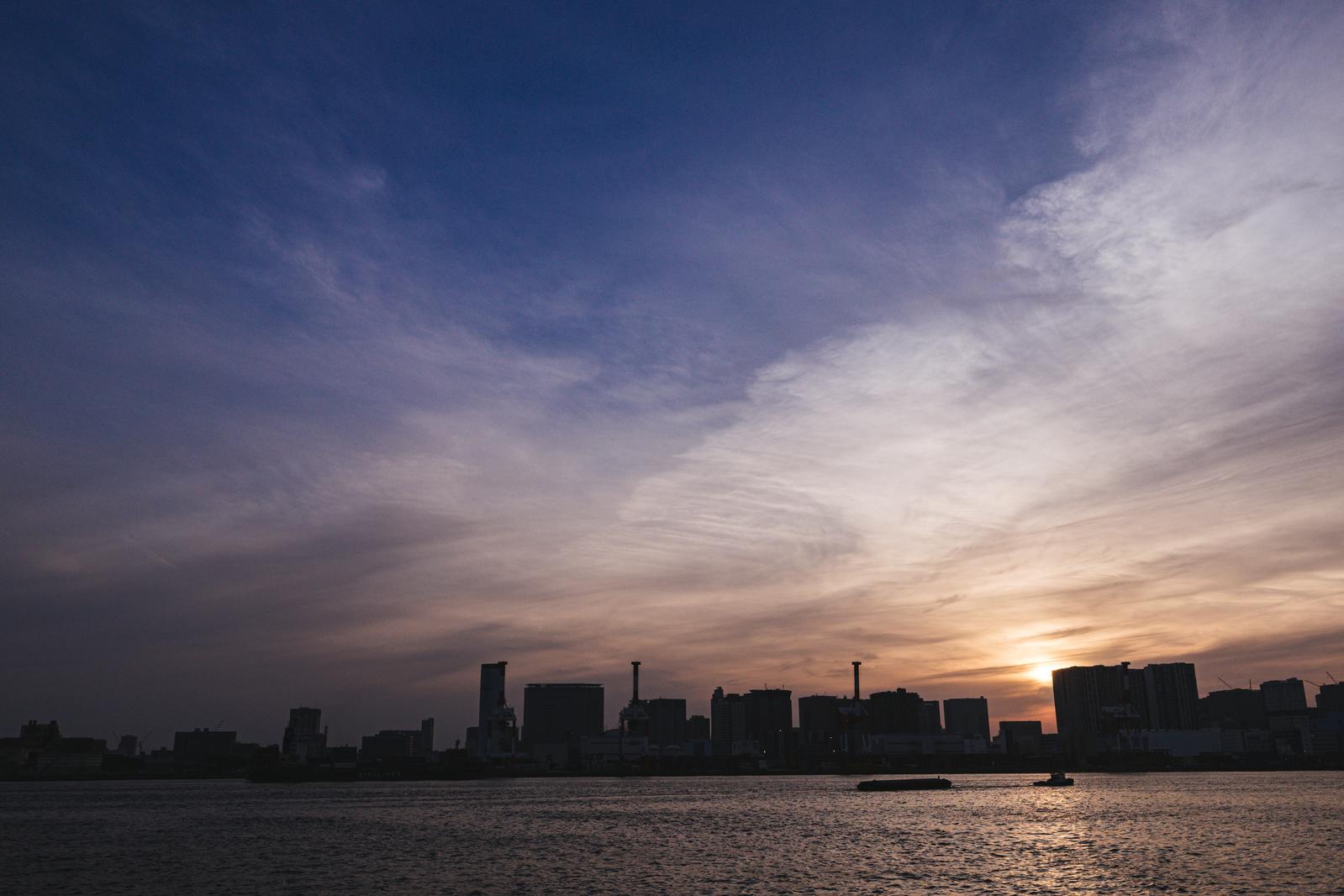 夕焼けに染まる海沿いの都市ビル群のシルエット