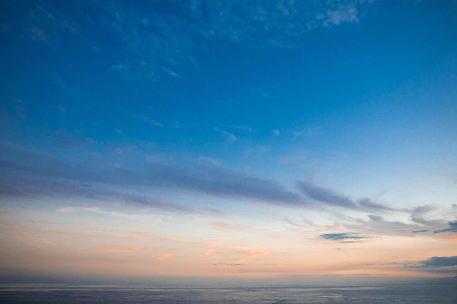 青空から暖色系の夕焼けへとグラデーションする空と雲