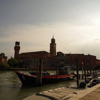 夕暮れ時のベネチア、運河沿いの船着き場と歴史的建造物の写真