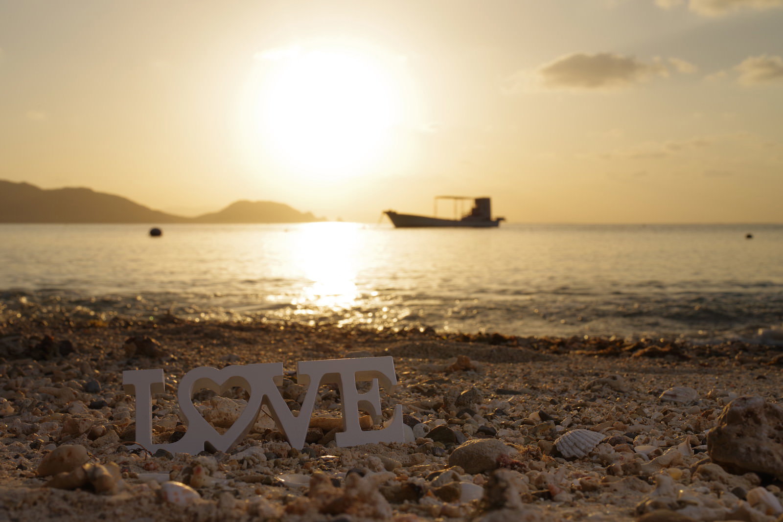 夕暮れの砂浜に置かれたLOVEの文字オブジェクト