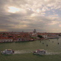 行き交う水上バスと夕暮れ時のベネチアの水路の写真