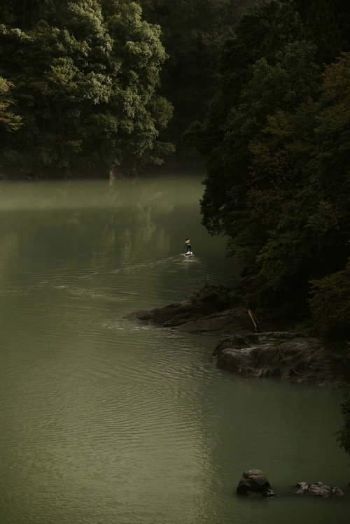 奥多摩の山中の川でパドルボートを楽しむ男性