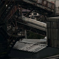 廃工場の古びた機械設備と錆びた配管が複雑に入り組む工場内の写真