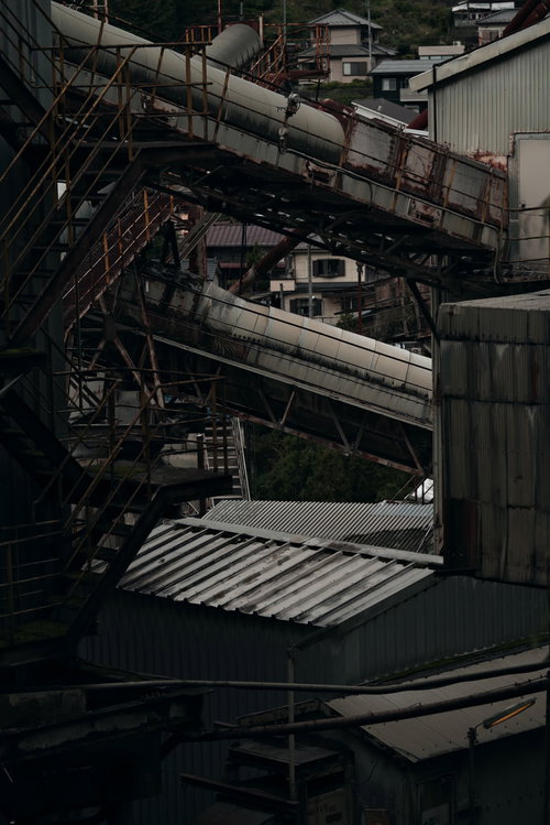 廃工場の古びた機械設備と錆びた配管が複雑に入り組む工場内