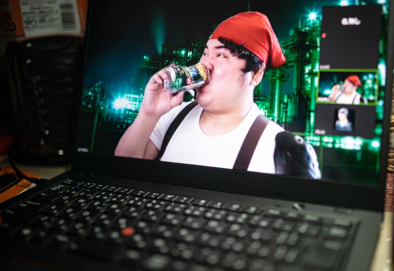 赤いニット帽をかぶった男性がパソコンでリモート飲み会をしている［モデル：段田隼人］